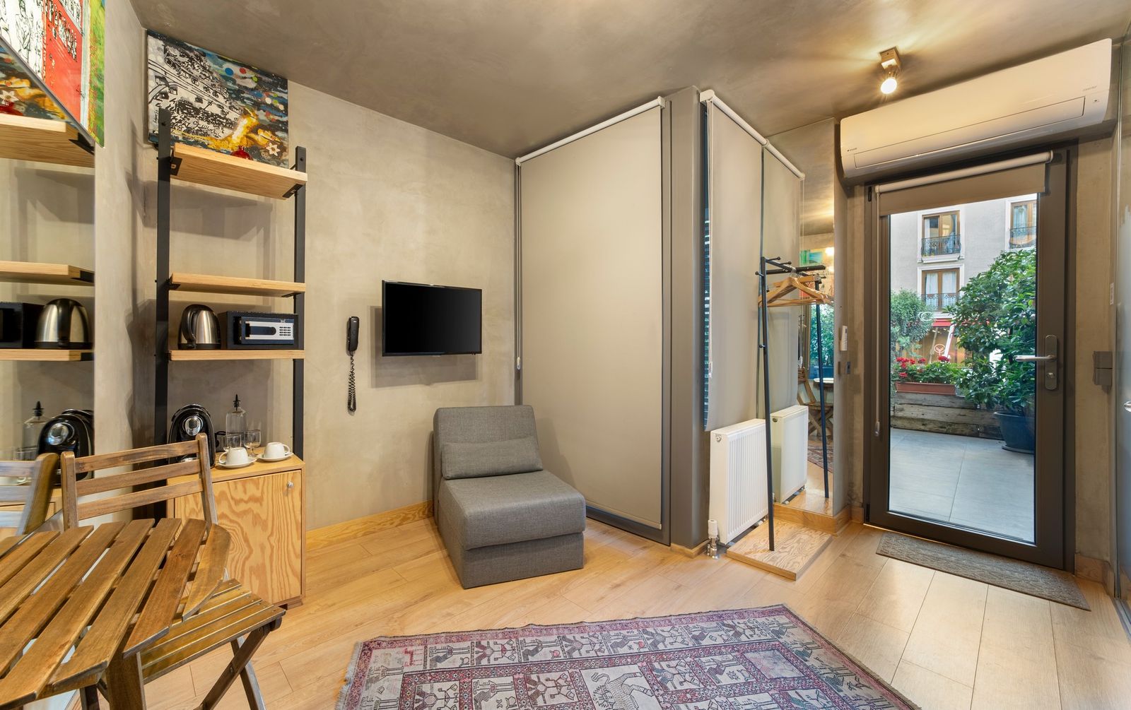 The interior of the Balcony Apartment seen from the entry — bed at the far end, the small dining table by the French doors.