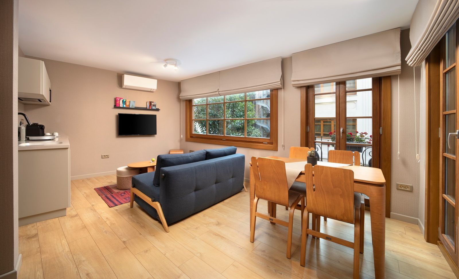 The lower-level living room of the Duplex Residence — long sofa, oak coffee table, north-facing window onto the courtyard.