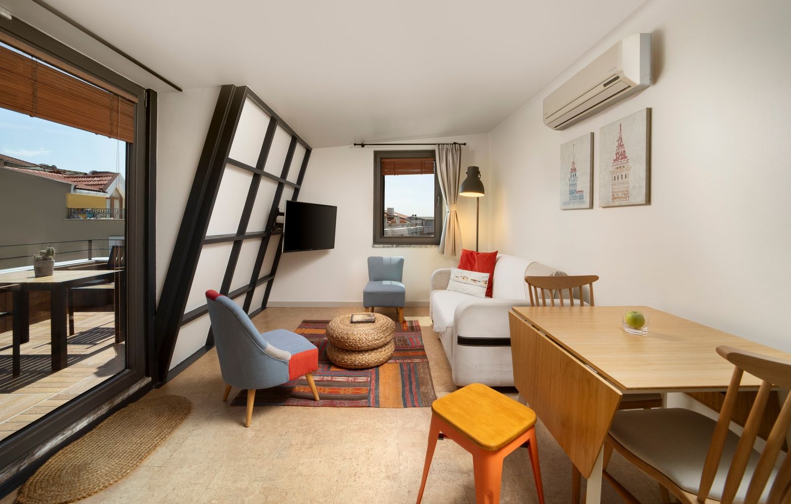 The living half of the Terrace Suite — the L-shaped sofa, the bed beyond, the door to the terrace open at the side.