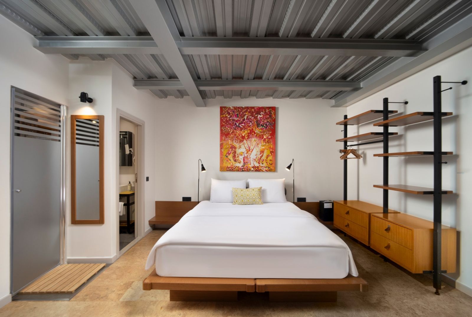 The bed of the Patio Room seen head-on, low ceiling with the original beams visible above, linen headboard against soft plaster.