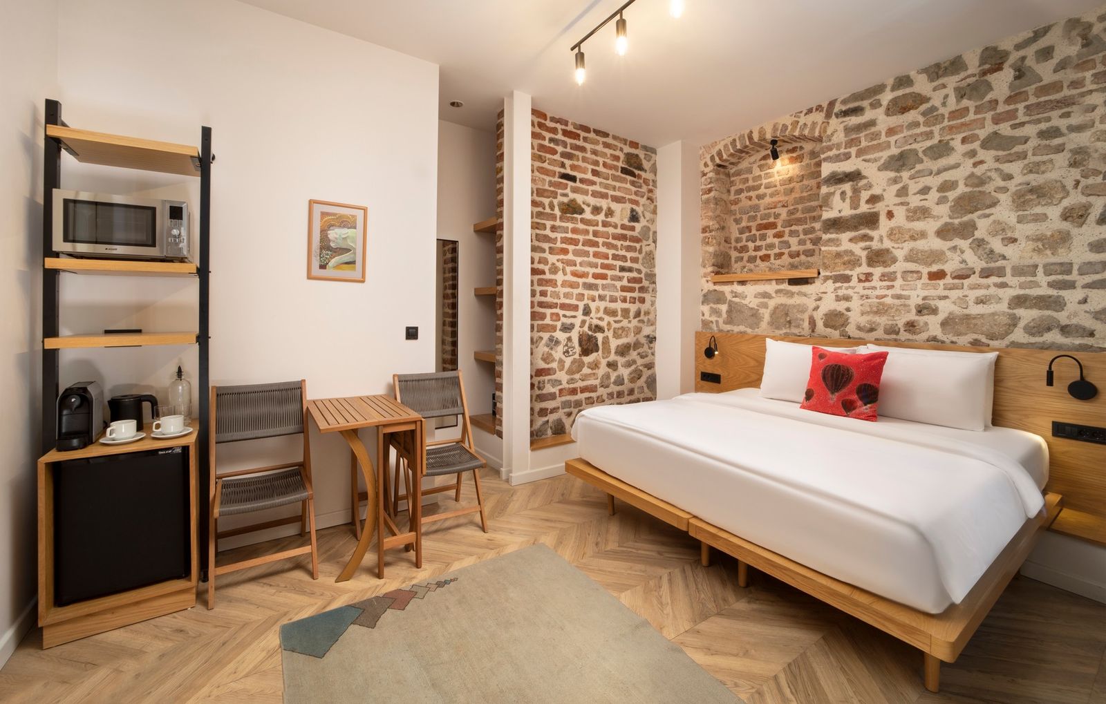 A wider view of the Studio Flat showing the bed, the dining table, and the compact kitchenette along the side wall.