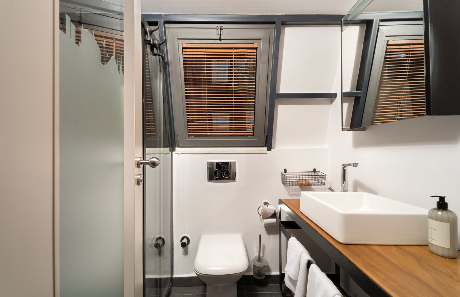 The bathroom of the Terrace Suite — large walk-in marble shower, brass rain head, towels folded on a wooden bench.
