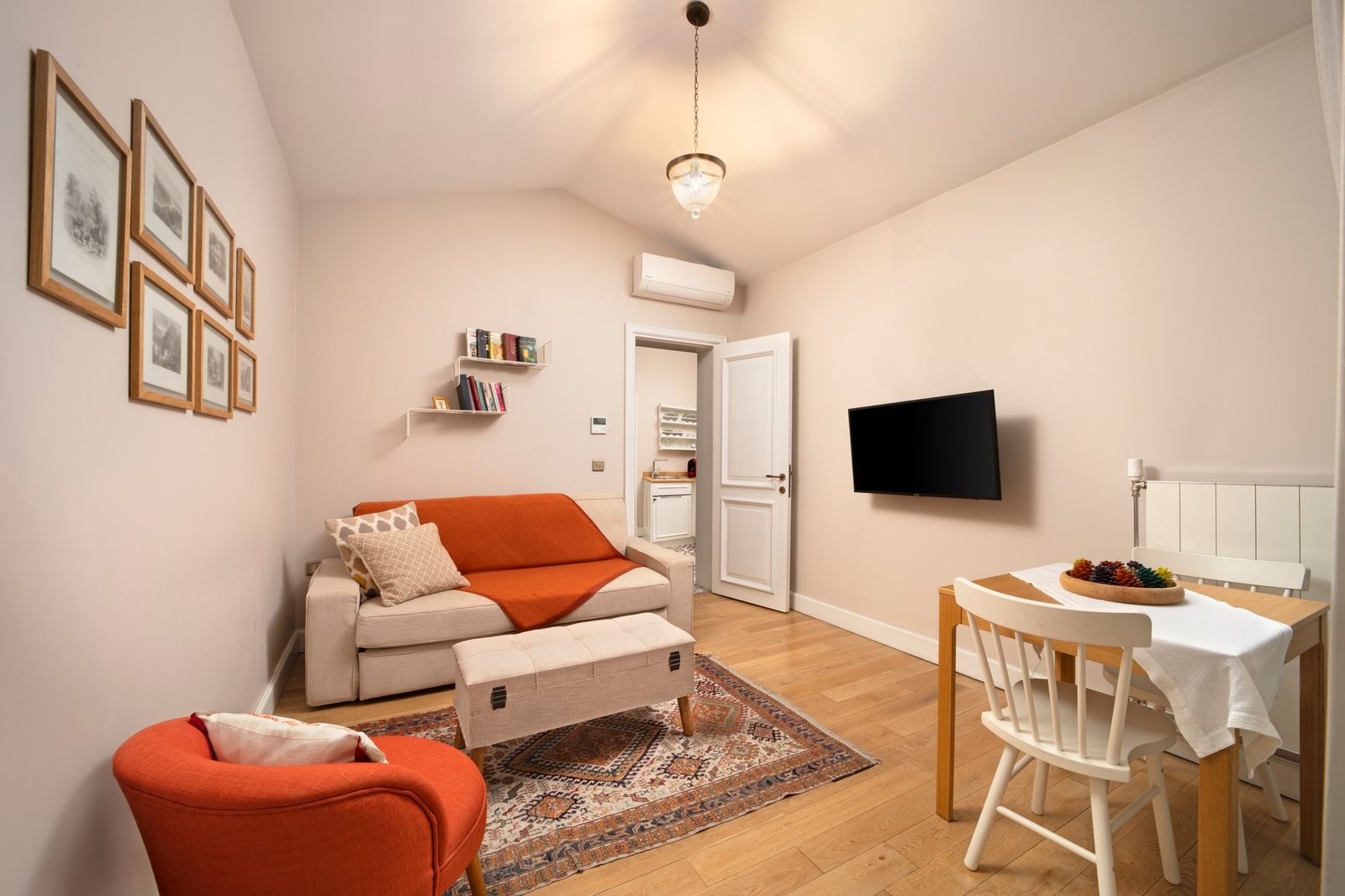 A wider view of the living room of the One-Bedroom Apartment with the balcony curtain backlit by afternoon sun.